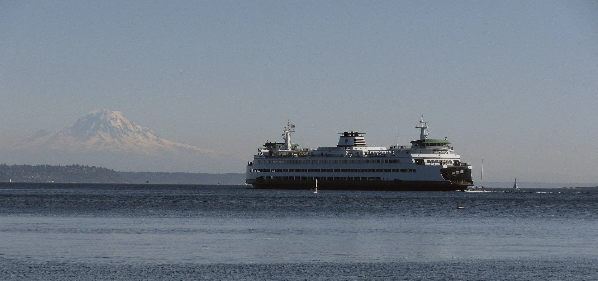 A ferry crossing open water with mountains in the distance